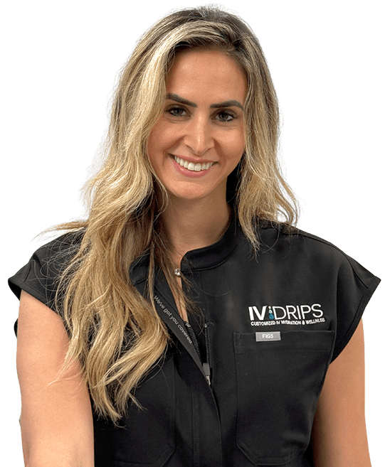 A woman with long blonde hair, wearing a black IV Drips uniform, smiles at the camera against a plain light background.